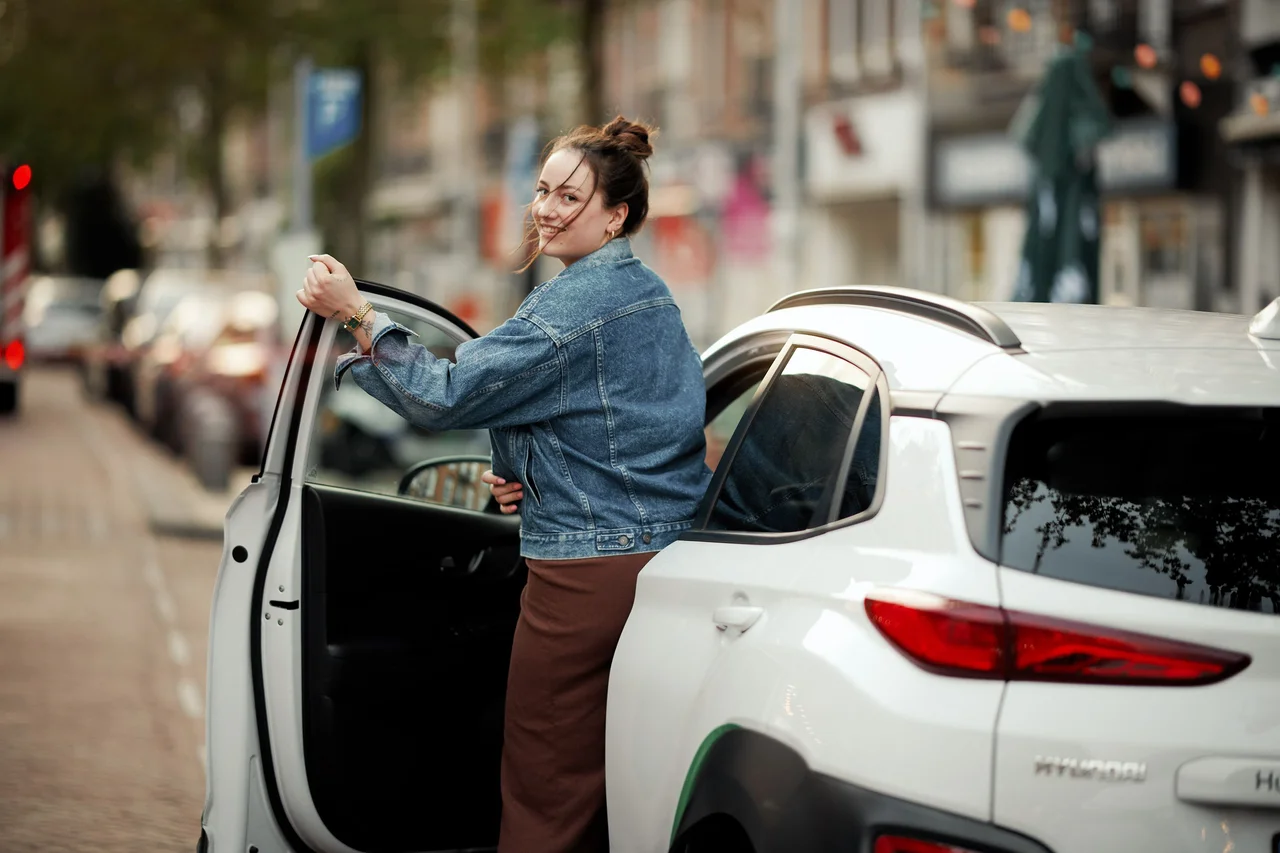 Vrouw in MyWheels deelauto kijkend naar achter