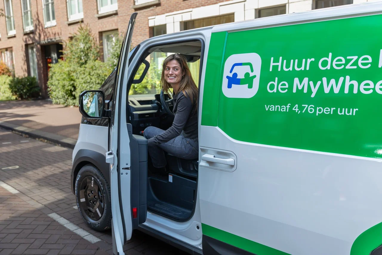 Vrouw zit lachend achter het stuur van Kia PV5