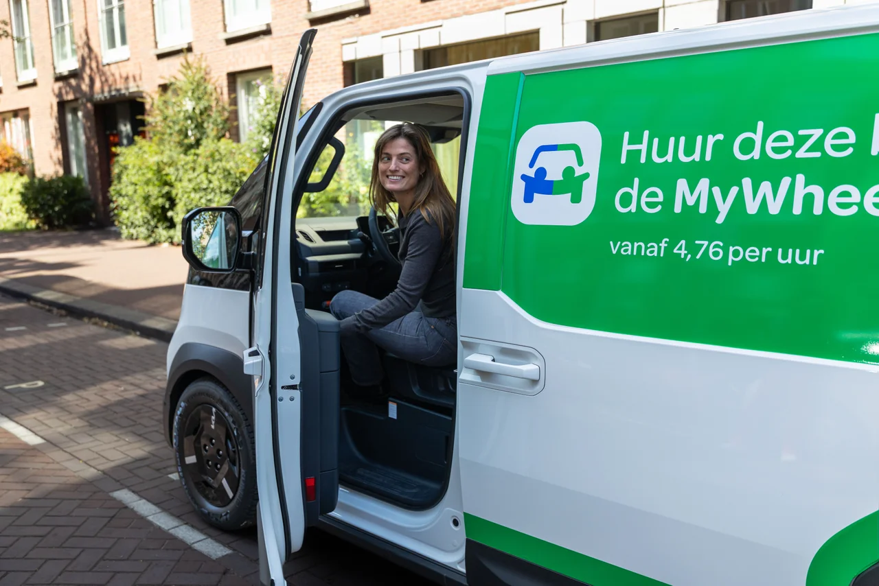 Vrouw zit lachend achter het stuur van Kia PV5
